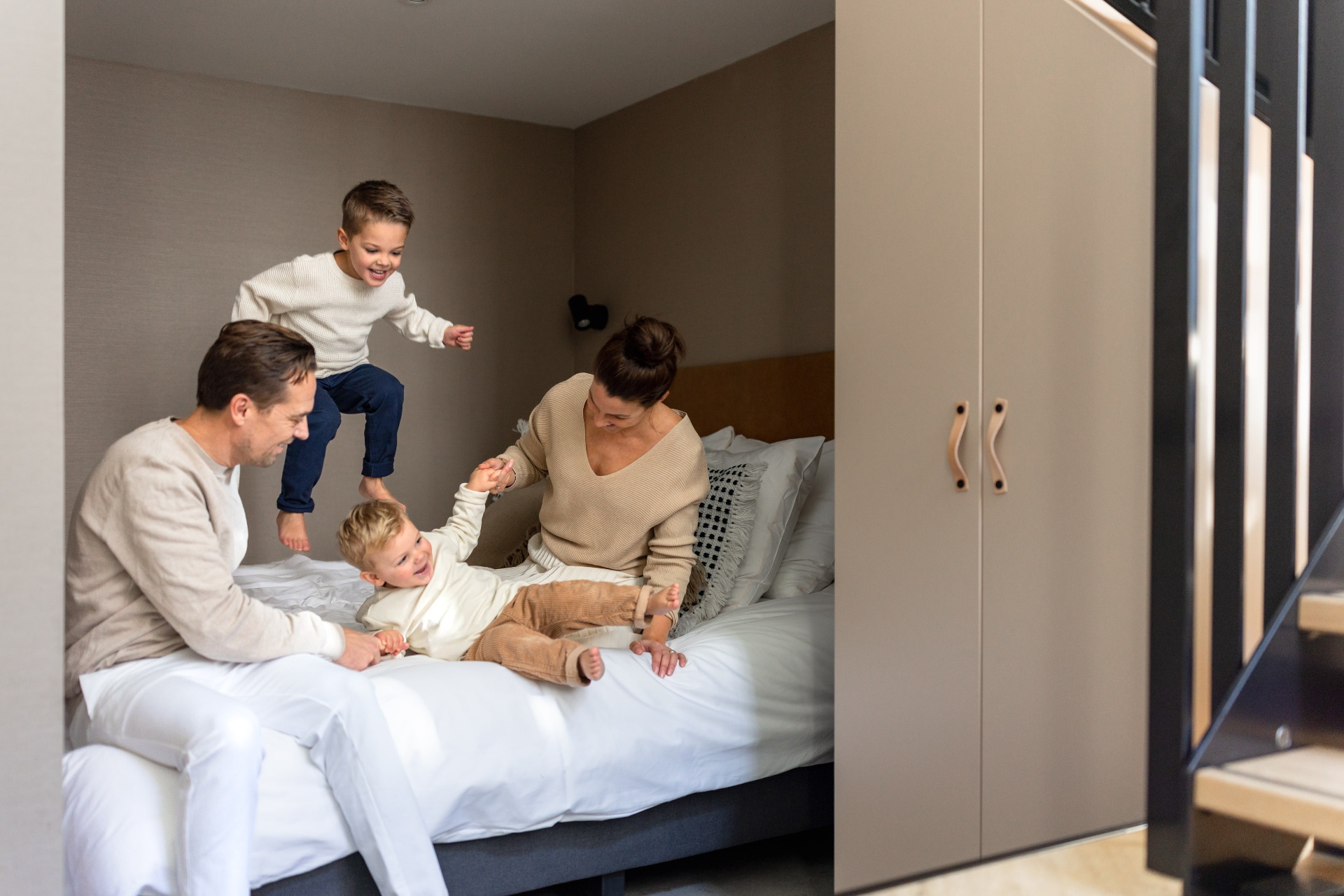 Family playing on the bed in their apartment